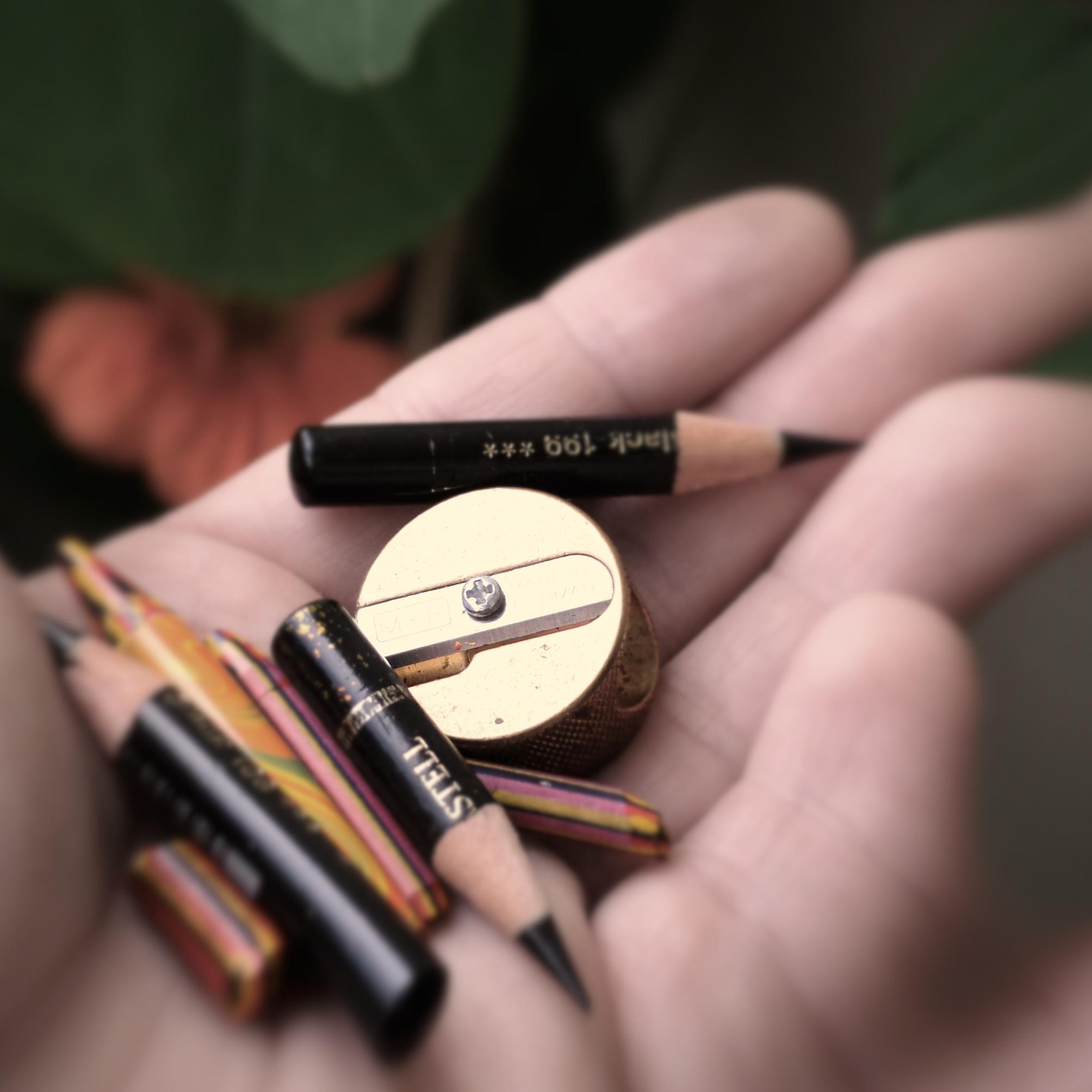 A handful of short coloured and black pencils and a golden sharpener, macrophotograph