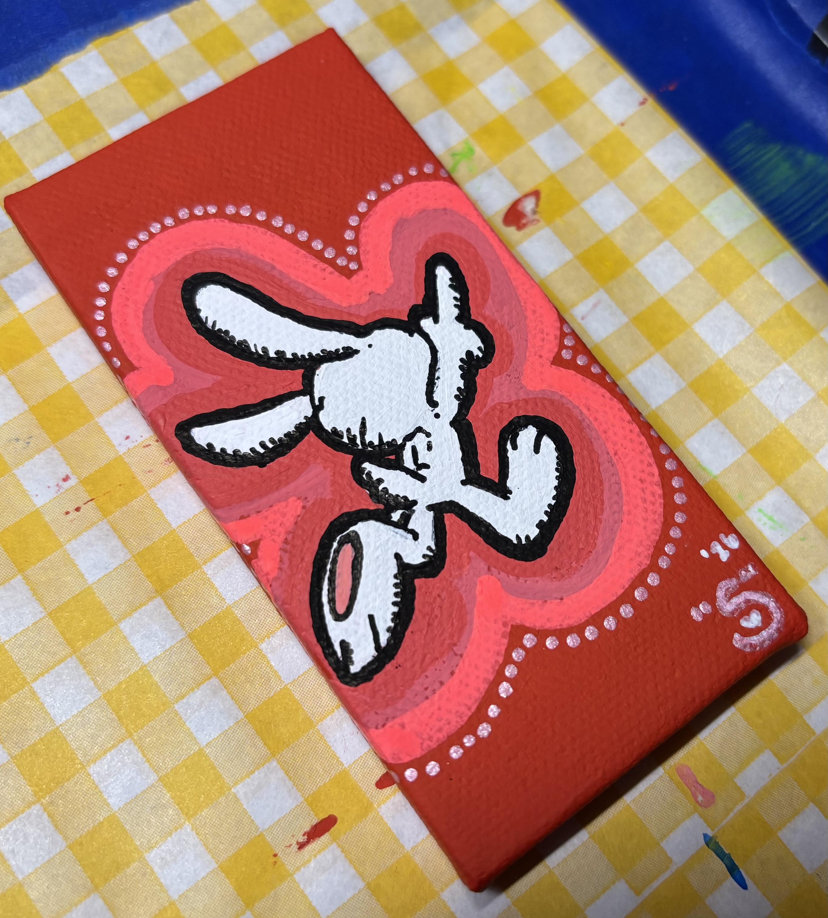 a small vertical rectangular canvas painted in red with a white cartoon rabbit in the middle, running away from the viewer and pointing up in the air with one finger. there's a neon red and naphthol pink outline around the rabbit, as well as several small pink glitter dots surrounding the edge of the outline.