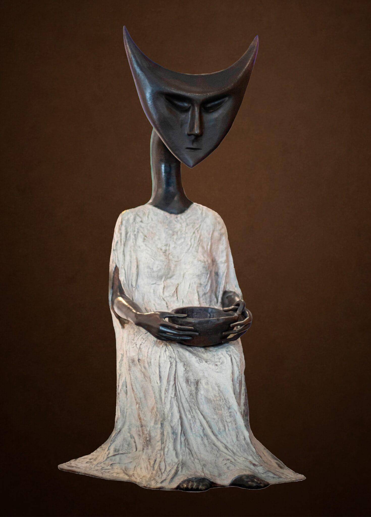 a bronze sculpture of a surreal figure with a geometric head and white robe, holding a bowl
