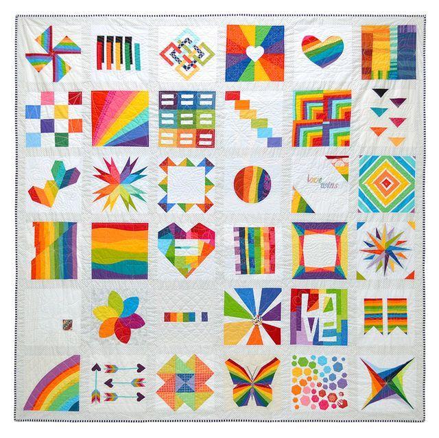 Sampler quilt, shown in full. The pattern is a 6x6 grid of blocks, with each block featuring a rainbow design set on a white background. Designs include hearts, a butterfly, a pinwheel, log cabins  and equal signs as well as some improv pieced and curved rainbows.
