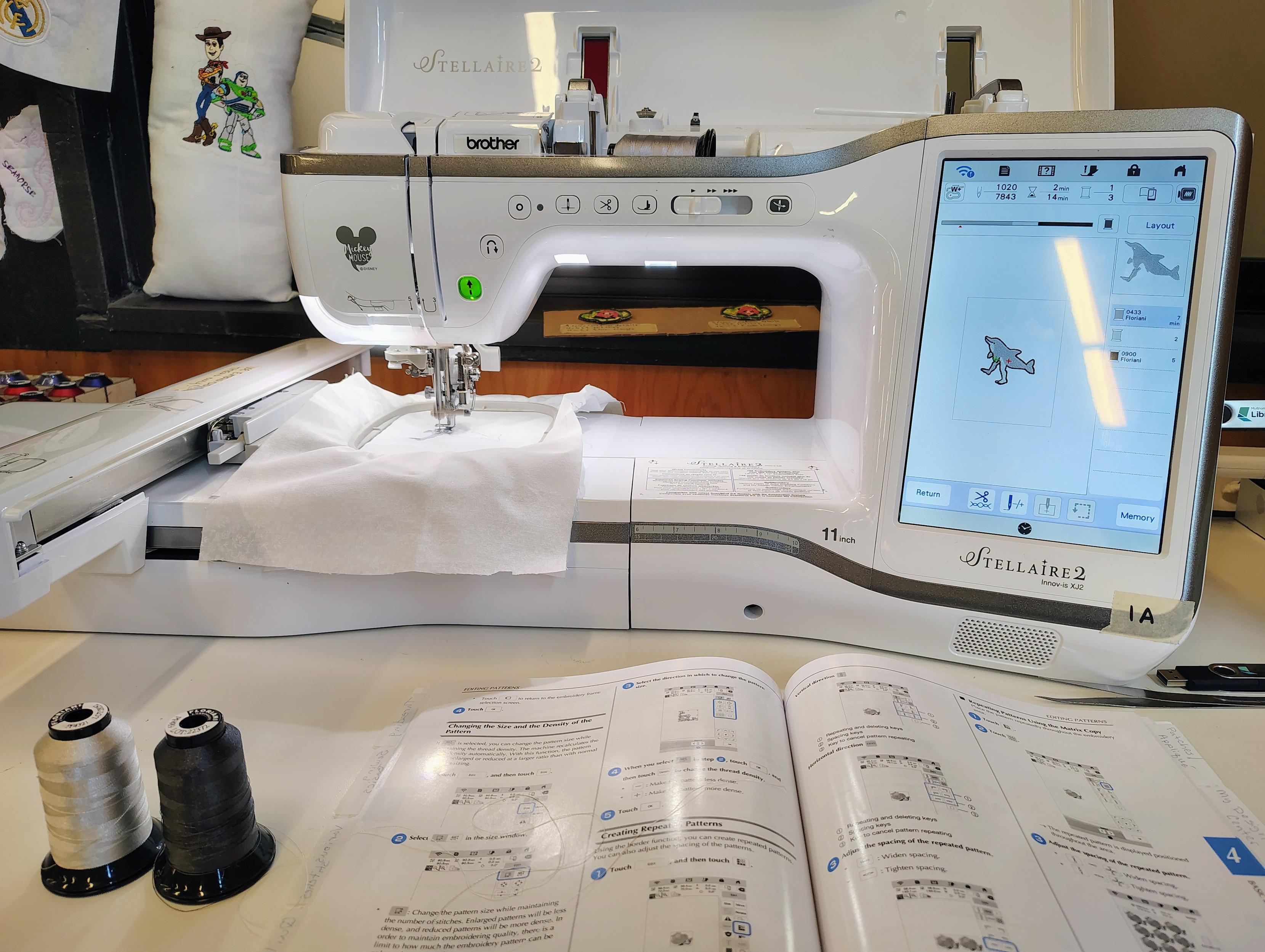 A brother stellaire embroidery machine with a touchscreen. The design has three colors. On the table are the other two thread spools.