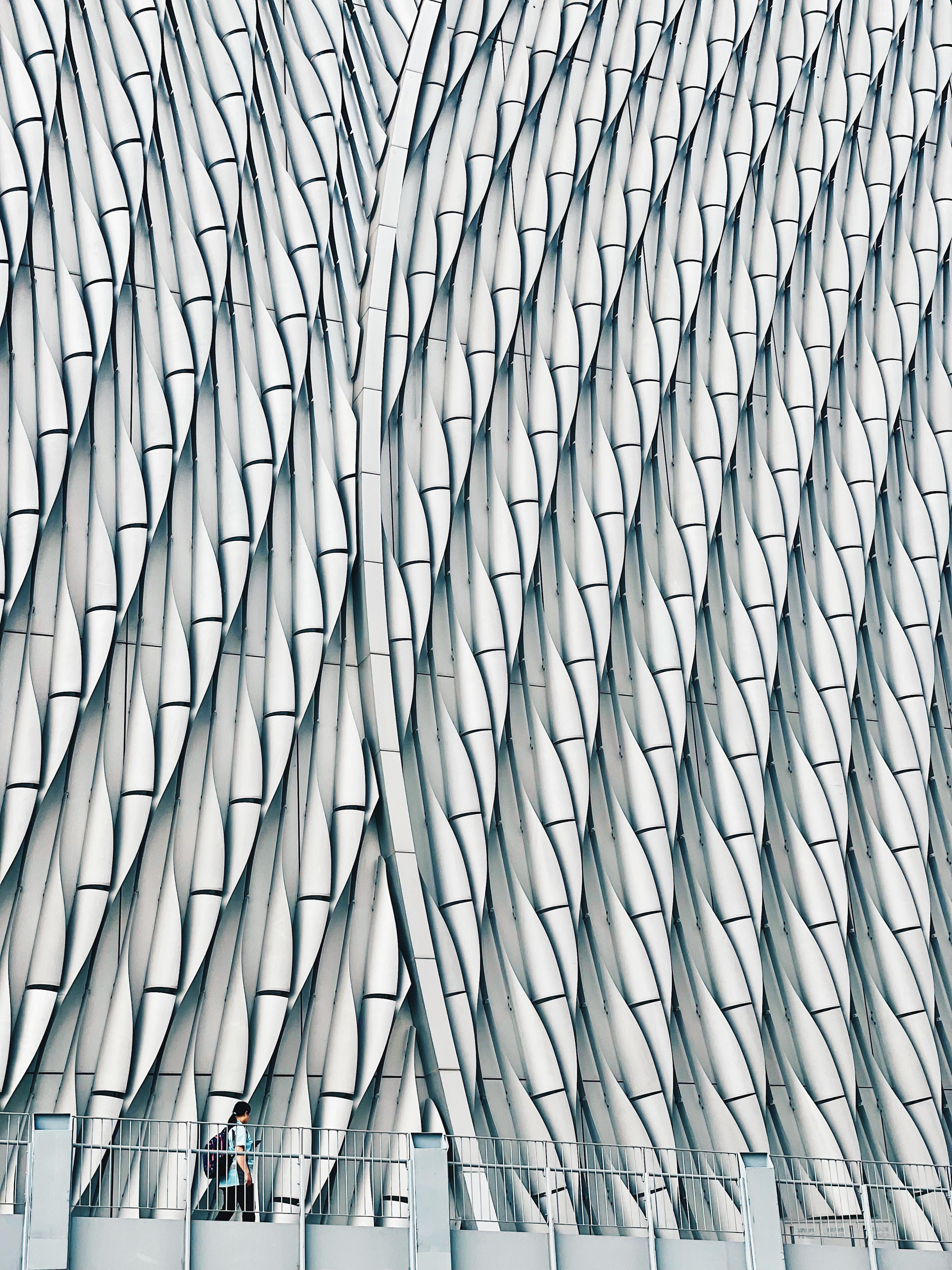 iPhone 12 Pro photo by Chicago artist Jenny Lam of a woman walking across the outside of the Xiqu Centre (part of the West Kowloon Arts District) in Tsim Sha Tsui, Hong Kong, March 2026