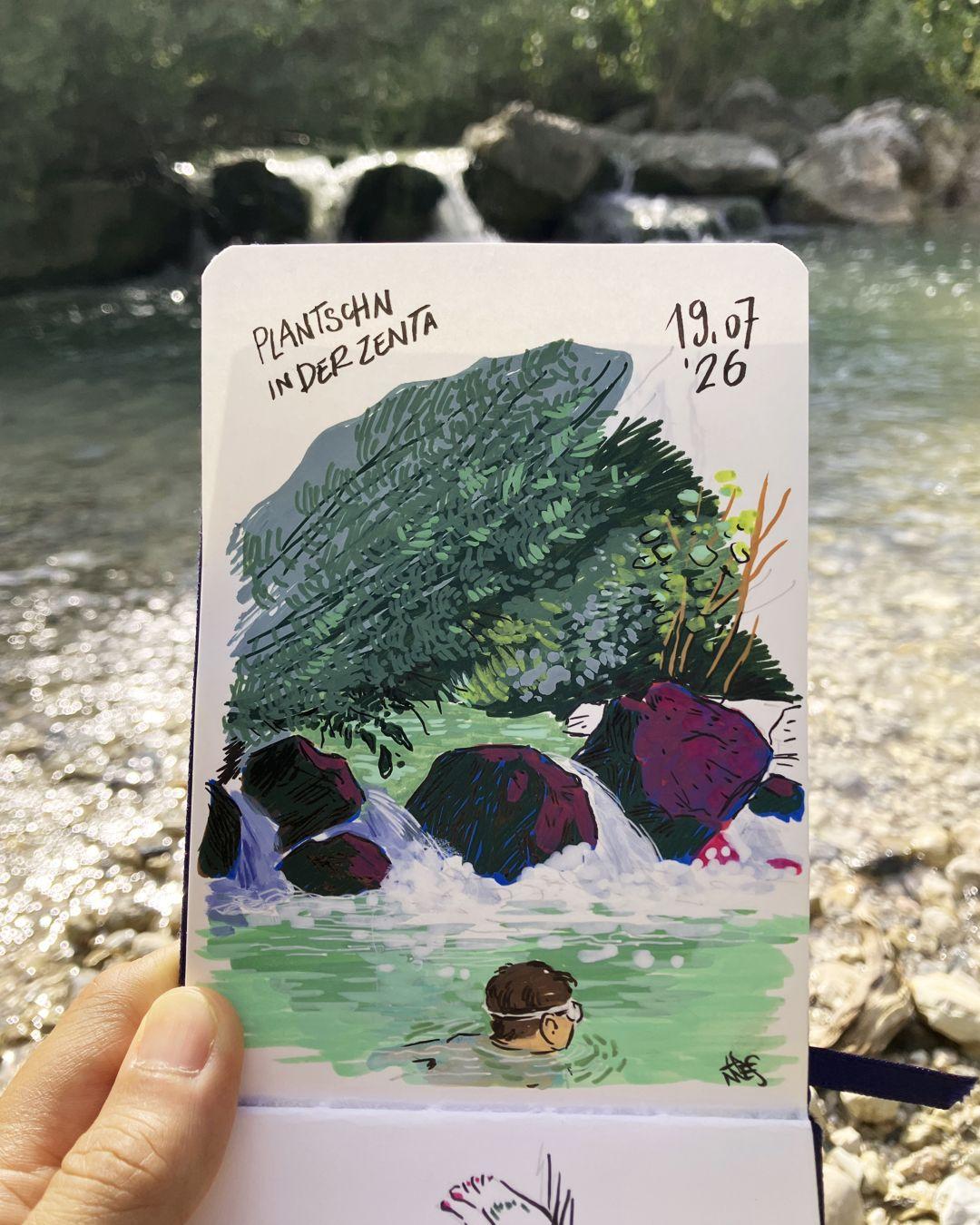 Photo of a sketchbook held open in front of the location that has been drawn. The drawing shows a little pond along a torrent, below a small waterfall. The torrent flows out from between low trees and bushes. The water is green-blue. A child is swimming in the middle of the pond.