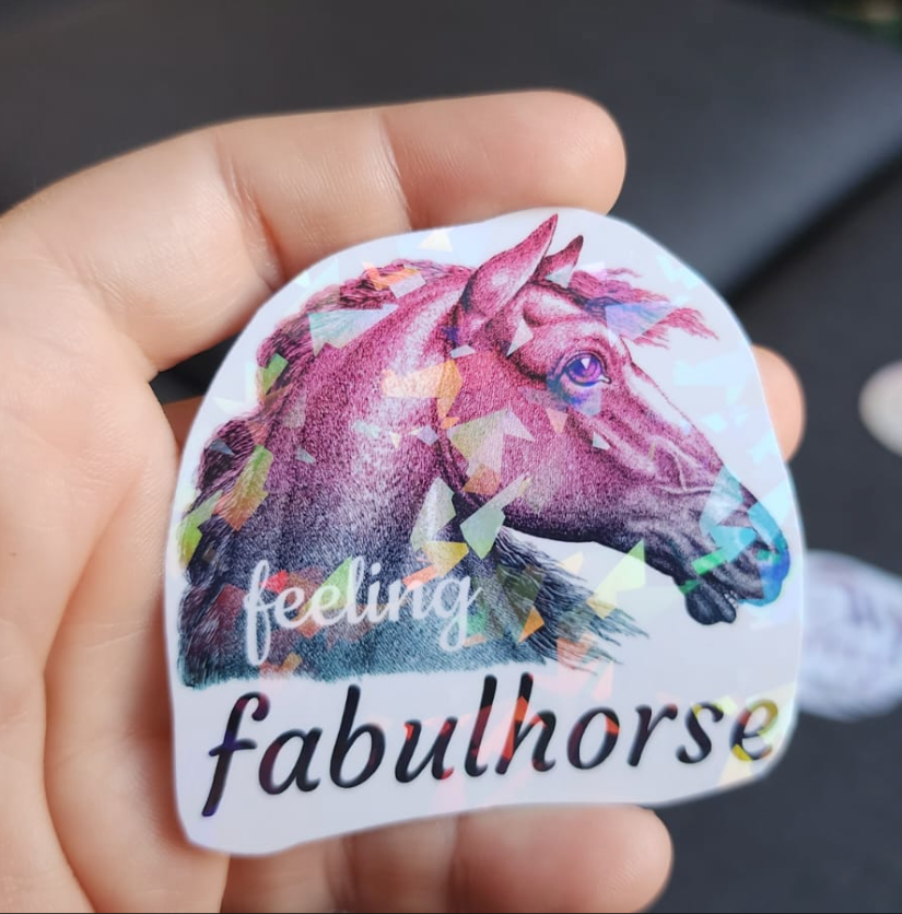 A holographic sticker with a vintage horse illustration in pink and blue from the neck up, with the words 'feeling fabulhorse'.