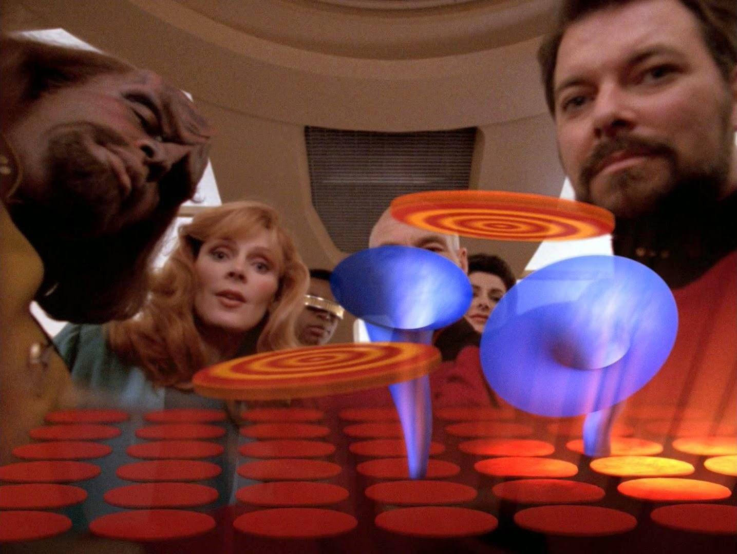 Still image of star trek TNG episode "the game" where the bridge crew forcibly look down on the camera view (I think it was the view of Wesley crusher after they forced him to play the game). 
There's a game playing field in the foreground with a board, some discs and funnels.