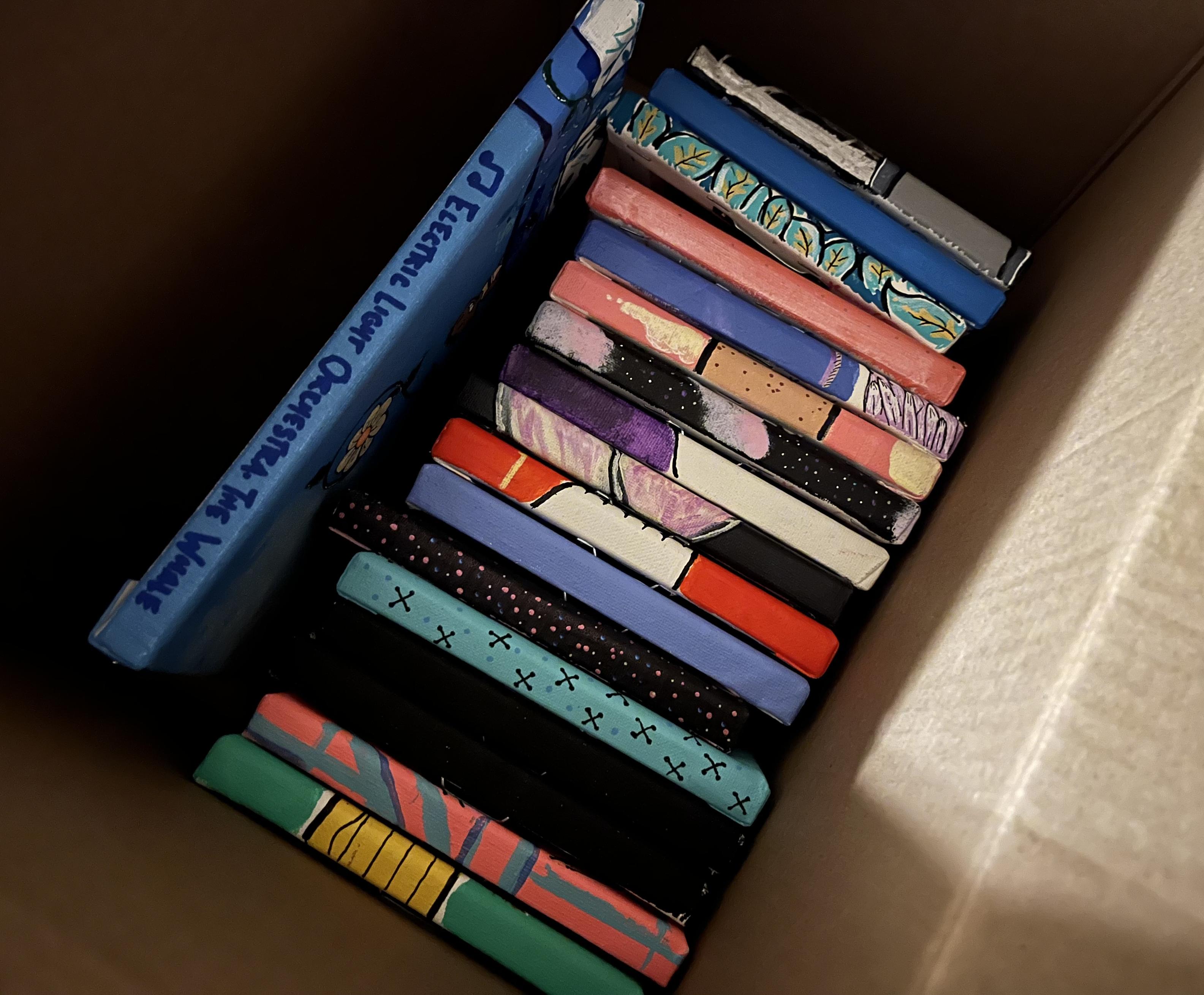 a cardboard box with several of my 6 x 6 paintings at the bottom.
