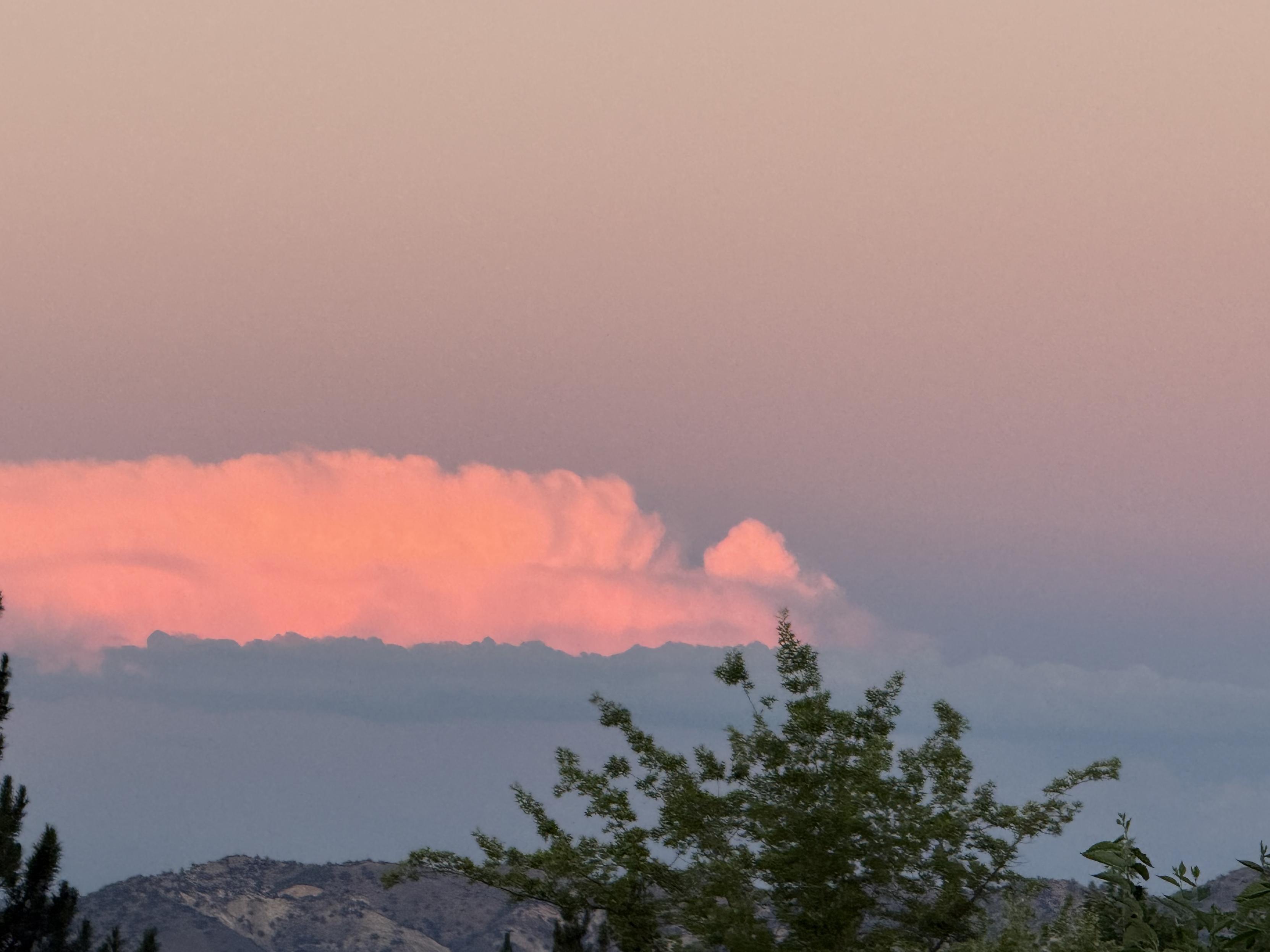 In the sky that is opaque-pink/blue-gray gradation, there's a band of very active, bright pink cloud. Right below it, there's an ocean of blue cloud waves.