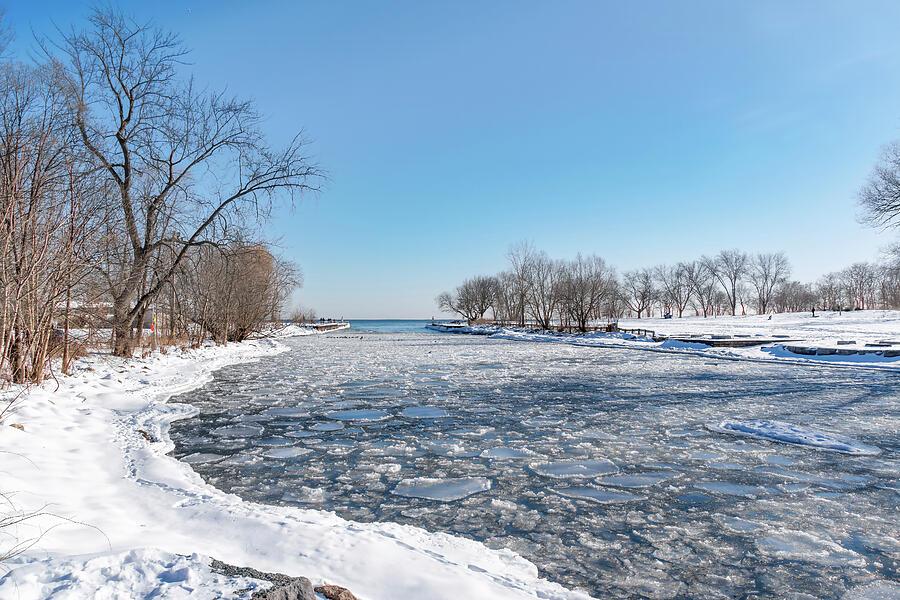 The partially frozen water of Etobicoke Creek heads out to Lake Ontario on a beautiful sunny but extremely cold winter day in Marie Curtis park in Toronto.