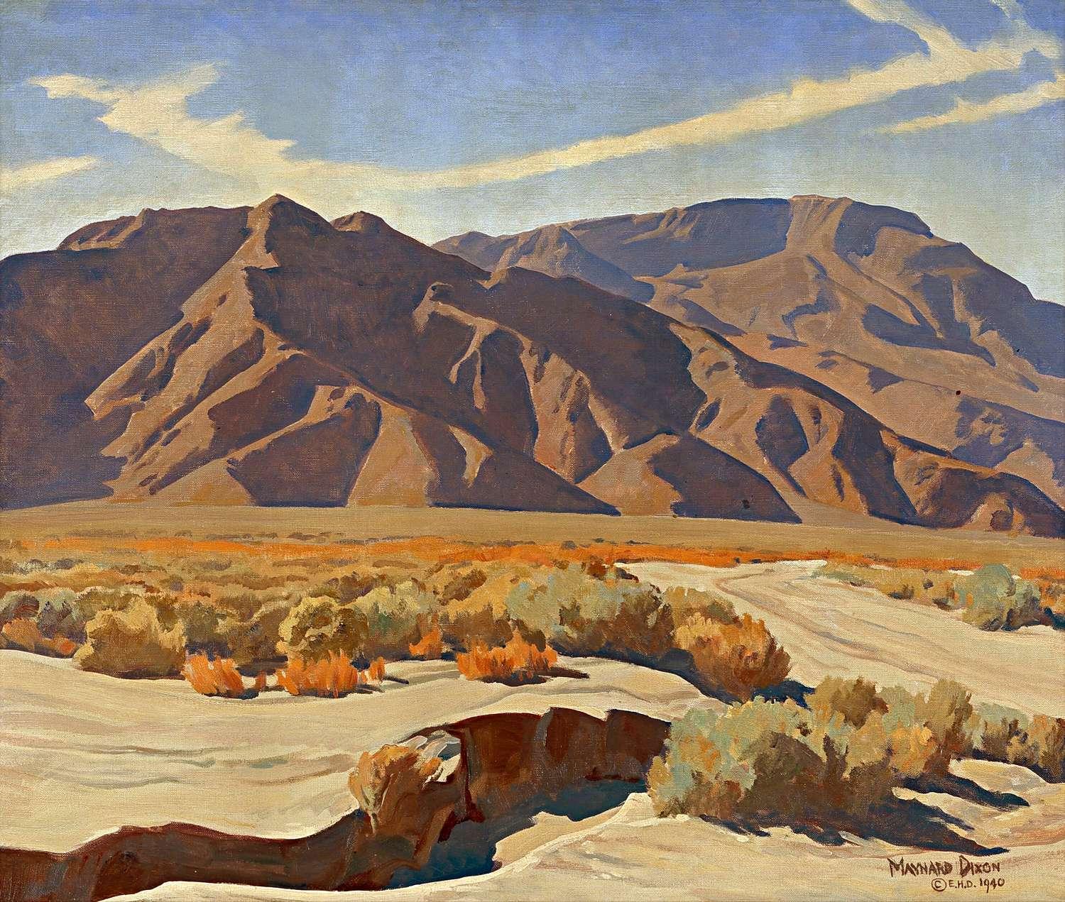 In the foreground, an arroyo or deep earth wash cuts dramatically into the sandy terrain, surrounded by a rich variety of textured desert brush and low shrubs painted in shades of sage green, gold, and vibrant burnt orange. A winding dirt track fades into the midground valley, leading the eye toward the massive, sun-sculpted peaks.