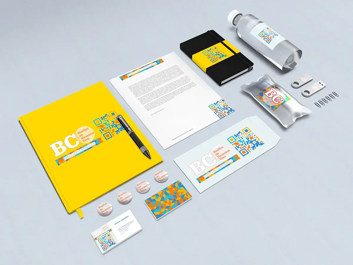 Papelería y objetos de marca de Banco de Contenidos: carpeta amarilla, hoja membretada, libreta, sobre, tarjetas, botones, memorias USB y botella con el patrón geométrico y el QR.