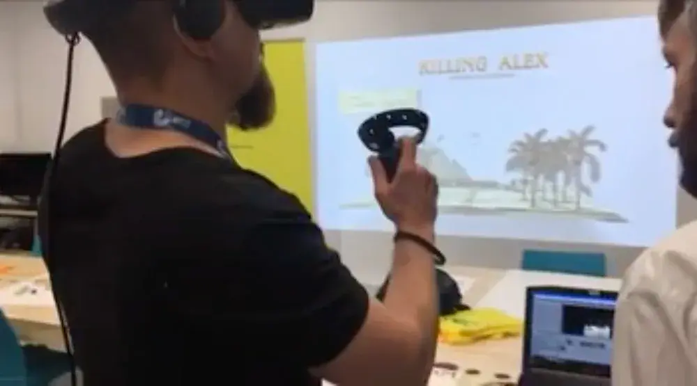 Una persona con visor de realidad virtual y control en la mano prueba Killing Alex frente a una proyección del juego.