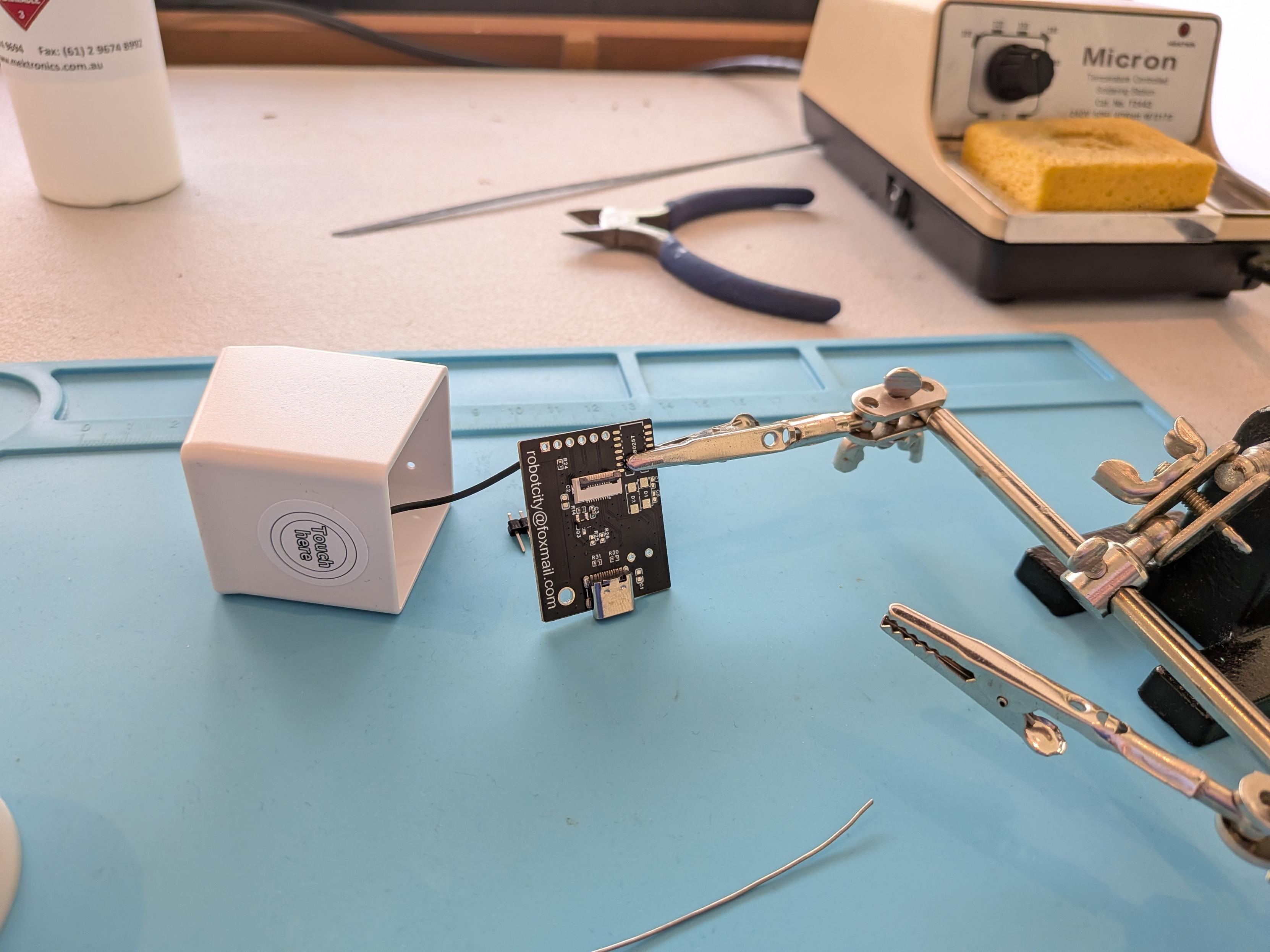 Small TV PCB in alligator clip ready for soldering on pin headers.