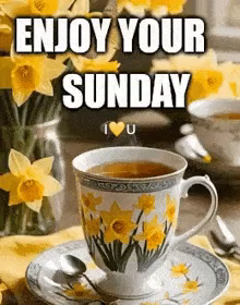 a cup of tea is on a saucer next to a vase of yellow flowers .