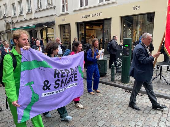 People on march, some holding a banner that says Repair & Share