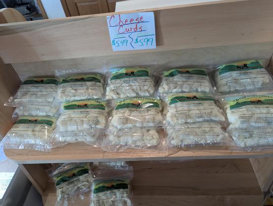 A bunch of fresh cheese curds all stocked up on a shelf, not refridgerated