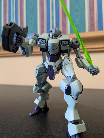 The HG Zowort pointing a gun above the viewer and holding a beam saber in a ready position