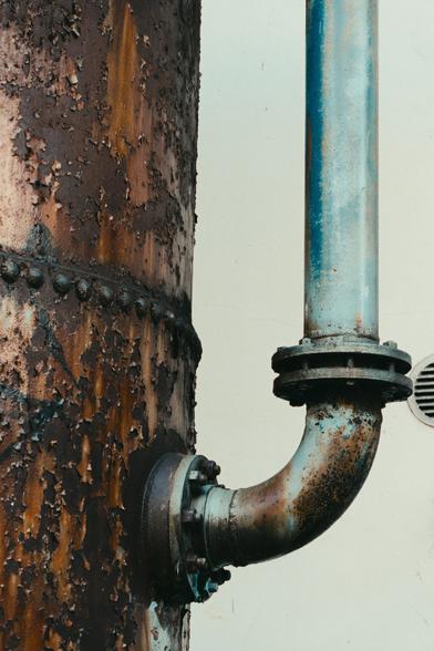 A closeup shot of a very rusty pipe. Another, smaller blue pipe is coming out of the larger pipe