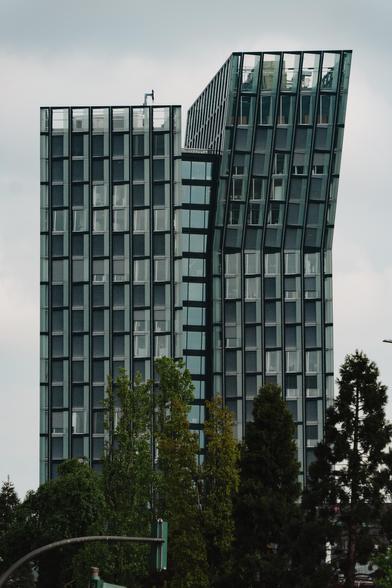A large skyscraper made up  from two building segments. The right tower is skews towards the right at a slight angle at the top, giving the building a fascinating shape