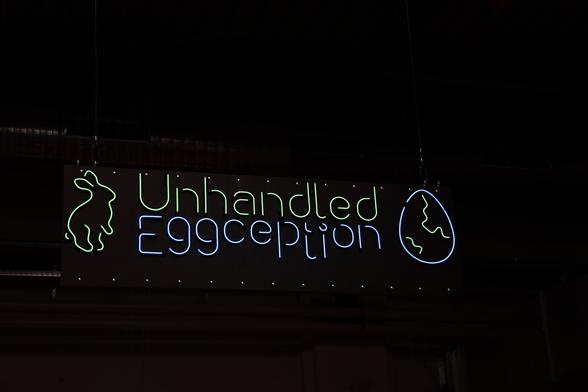 Big sign with the EH logo "Unhandled Eggception" with bunny and egg, made out of LED tubes. It glows in green and blue and matches the logo font nicely.