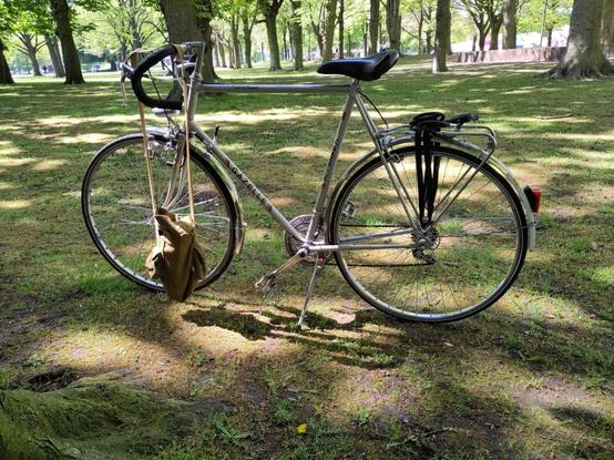 1980 grey Gazelle racing bike on the grass in a park. A little bag is hanging from the steering bar.