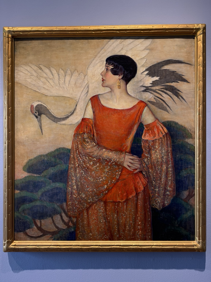 photo of painting #2 in gold frame  “The diverse Art Deco style of geometric forms, modern luxury, & bold vibrant color palettes reflected the social & technological progress of the 1920s & 1930s. Visual artists felt its influence, as modernity impacted nearly every medium. Among these artists was the Long Island-based F. Edwin Church…. Esteemed for his portraits of women that reflected the growing Euro-American interest in Japanese art, he painted a variety of subject matter, including luxurious portraits, displaying versatility in technique. He captured beaming skin tones & ornately textured fabrics, captivating the viewer with dramatic compositions. Throughout the late 1910s into the 1930s, Church painted various women in verdant Japanese-inspired settings. Lady in Charlotte's Dress, 1928, is quintessentially Art Deco, with the bob-haired subject's graceful draped red dress evoking a sense of refined beauty.” Bird behind woman: Red-Crowned Crane