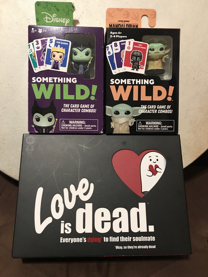 Card games: love is dead and Mandalorian and Maleficent versions of Something Wild! in front of Crissy’s Bendir frame drum