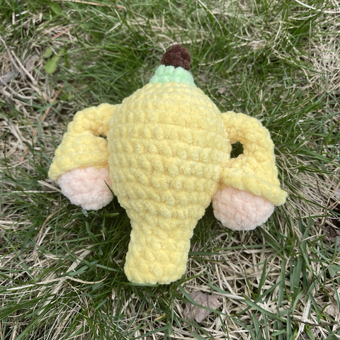 Banana-themed crocheted uterus. Yellow uterus with a banana stem at the top and ovaries that look like banana innards.
