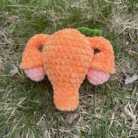 Orange-themed crocheted uterus. Orange-colored uterus with a green leaf on top.
