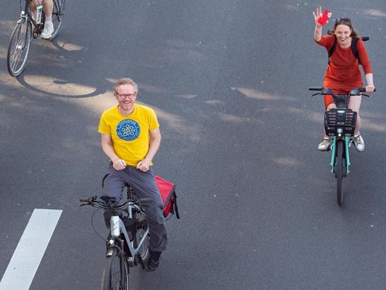 2 Menschen fahren nebeneinander auf dem Rad und lächeln dabei.