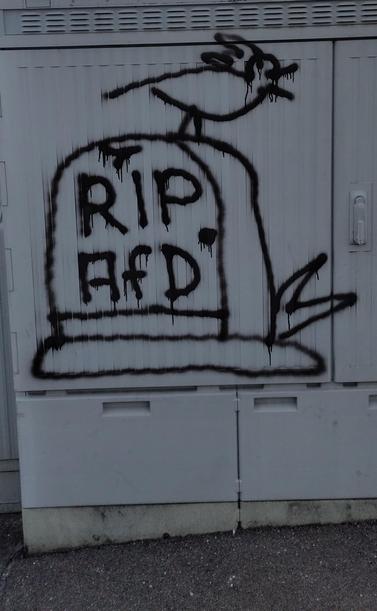 Graffiti, das einen Grabstein zeigt, auf dem "RIP AFD" steht und auf dem ein Vogel abgebildet ist, der anscheinend gerade seine Notdurft auf selbigem Grabstein verrichtet hat