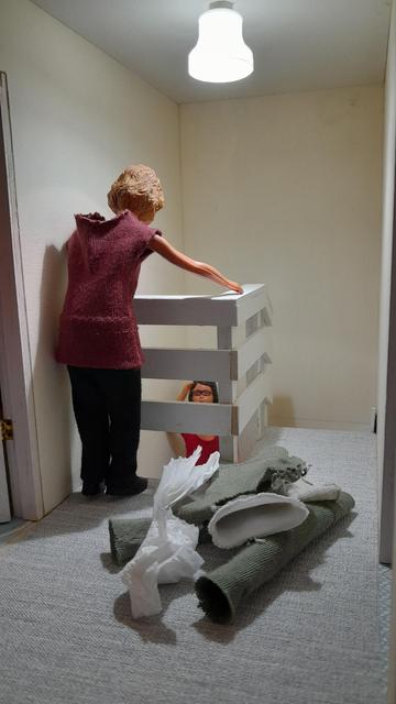 A 1:12 scale diorama of Daisy's upstairs hallway. The walls are magnolia, and there is a grey carpet. The stair well has a white painted banister of horizontal planks. There is a pile of clothes and towels on the floor.

Daisy, a Caucasian woman with fair hair and wearing a burgundy top and black trousers, is leaning over the banister at the top of the stair well looking down, with her back to the camera.

Harriet, a Caucasian woman with dark hair and wearing a red tee shirt,  can just be seen standing partway down the stairs, looking up at Daisy.

Daisy "Harriet, Harriet. Where for art thou Harriet?"

Harriet "Wassup, Daisy?"

Daisy "I was trying to be romantic!"

Harriet "But they, spoiler alert, died at the end!"

Daisy "Spoilsport! Anyway, it's that day again."

Harriet "Ahh yes. Okay, ummm....
"Daisy, Daisy, throw down your laundry!"

Daisy "Doesn't quite have the same ring to it, does it!"

Harriet "Nah. Oh well. Bring out your dead! They're going to the launderette!"