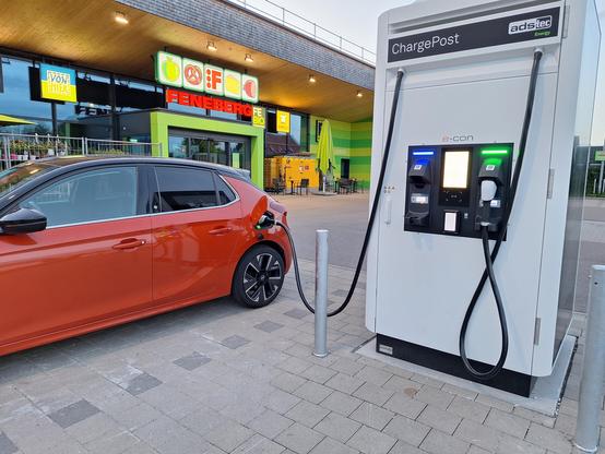Corsa ladet an einer Ladestation vor einem Feneberg Supermarkt