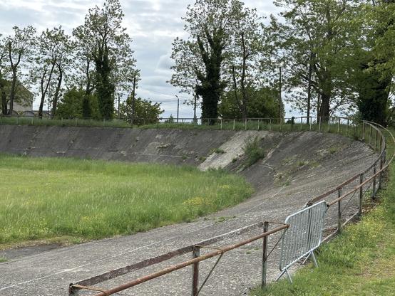 Photo d’un vélodrome extérieur en béton, ancien et pas entretenu, avec plein de fissures et de plantes qui se sont installées