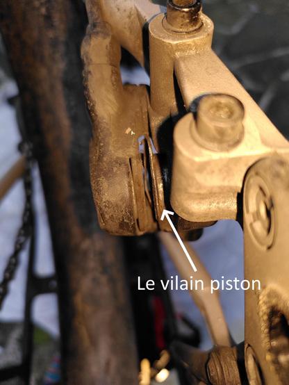 Photo commentée vue de près du frein à disque après démontage de la roue.
On peut voir le piston de droite qui est bien sorti (en gris), avec la plaquette complétement bouffée. C'est flagrant par rapport au coté gauche.