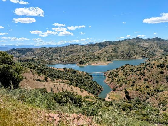 View of a lake from the top of a hill with mountains in the background