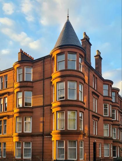 A red sandstone tenement featuring a corner tower topped with a candle-snuffer roof.