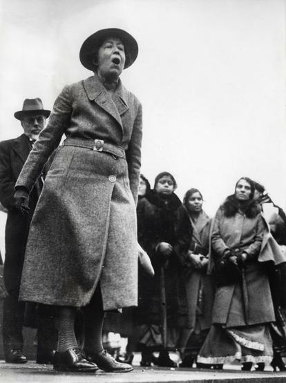 Pankhurst (in overcoat and hat) protesting in Trafalgar Square, London, against British policies in India, 1932. By Nationaal Archief - originally posted to Flickr as Suffragette Sylvia Pankhurst / Suffragette Sylvia Pankhurst, No restrictions, https://commons.wikimedia.org/w/index.php?curid=8005271