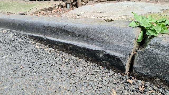 A lip worn onto an old kerb stone.
