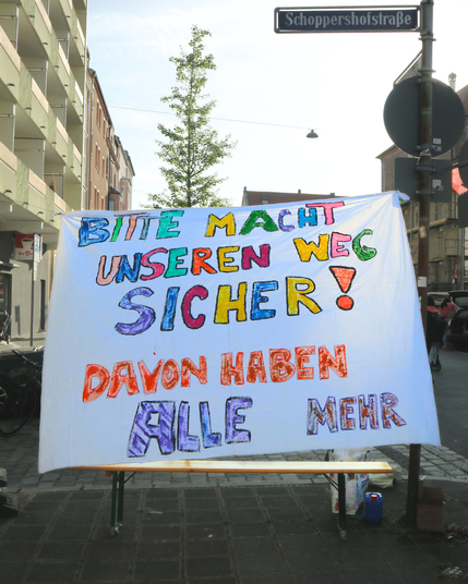 Foto von einem bunten selbstgemalten Banner: Bitte macht unseren Weg sicher! Davon haben alle mehr.