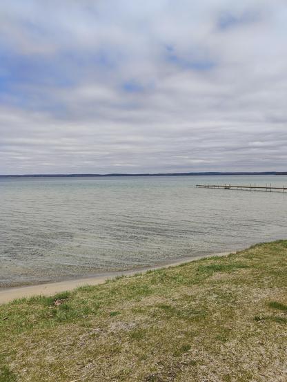 Higgins Lake looking out to the east. There is a dock in the water. The water is very calm.