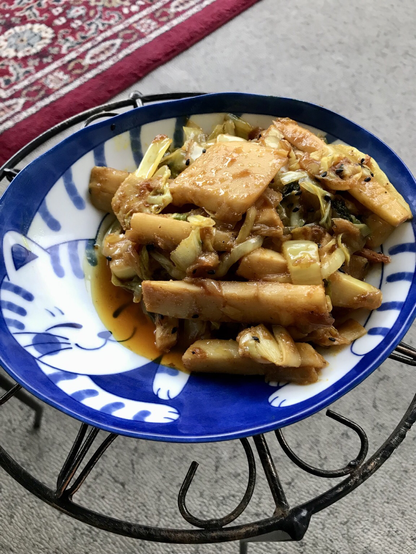 Crissy's stir-fried crispy bamboo shoots with black sesame seeds, 2 kinds of shredded cabbage, sautéed onions on a cat-themed plate of blue and white.