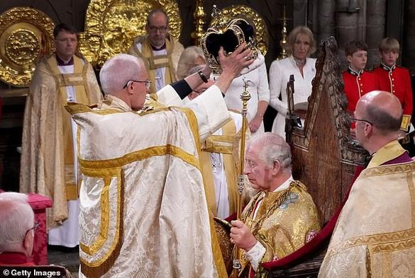 The archbishop very carefully places the crown on Charles's head