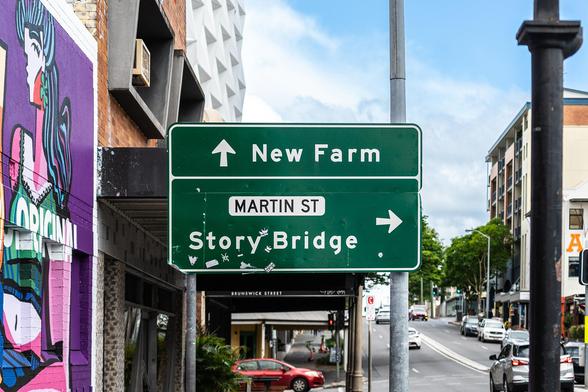 A street sign in Brisbane pointing to New Farm straight ahead and the Story Bridge to the right.