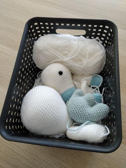 A black basket of crocheted body parts of a pegasus.