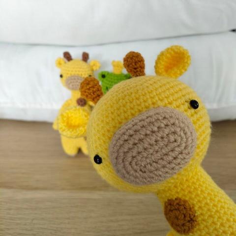 A tall giraffe pops up in front of the small giraffe and frog.