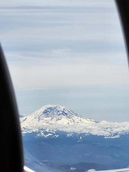 a lovely, symmetrical, snow-covered mountain, viewed out of the window of a little commuter jet.