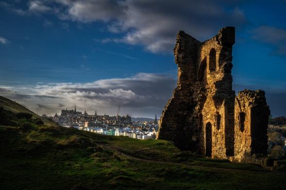 St Anthony's Chapel Ruins im Abendlicht; im Hintergrund ist Edinburgh zu sehen.