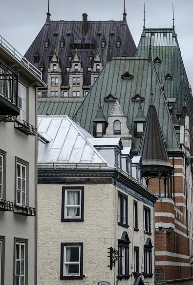 Multiple layers of buildings built in a centuries old architectural style in the heart of the old quarter of Quebec City in Canada, rendered in a muted earthy color palette.
