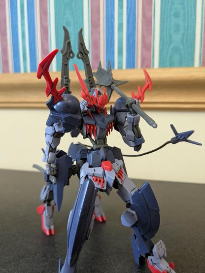 HG Barbataurus in a standing pose. Its right hand is resting on its sword, which is stored on its ... saddlebag unit? Its left hand is holding its mace over its shoulder. Both of its short swords are on its backpack pointed up.