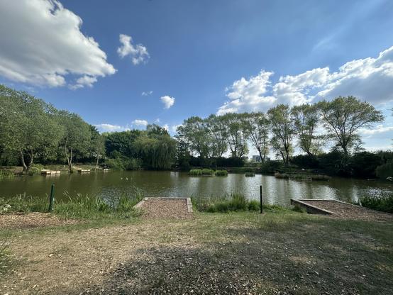 a wider view of the same pond, with tree-lined banks and calm water reflecting the vibrant sky.